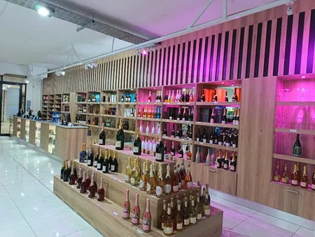 Commercial retail shopfitting with bespoke timber slat shelving, lit display bays, and POS counters — hospitality bar design by Wito Projects, Johannesburg