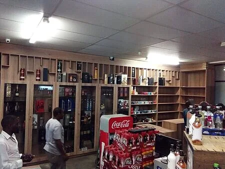 Wide interior: multi-station POS, illuminated undercounter spirits, and slatted timber feature wall—Gauteng bottle store