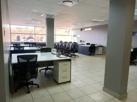 Modern open-plan office with white desks, black ergonomic chairs, and grey columns — Sany corporate workspace, Olifantsfontein Gauteng