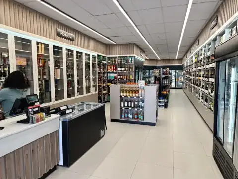 Premium spirits glass-front cabinets, timber-slatted checkout counter, and central display island at The Valley Cellar — Wito Projects shopfitting Johannesburg